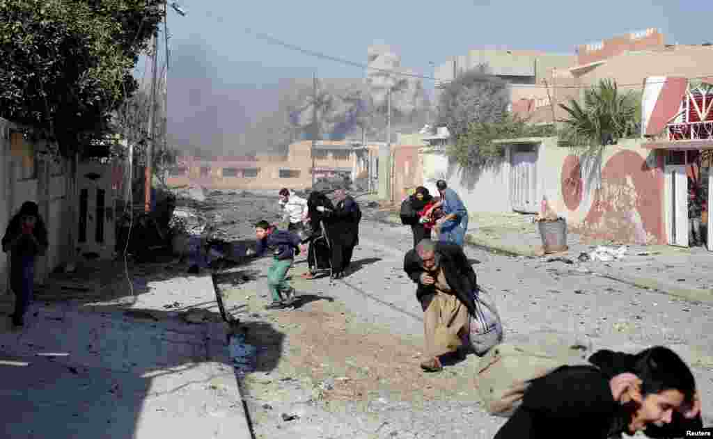 Warga sipil yang panik berlari menghindari serangan udara pasukan Irak terhadap posisi ISIS di distrik Tahrir, Mosul, Irak.
