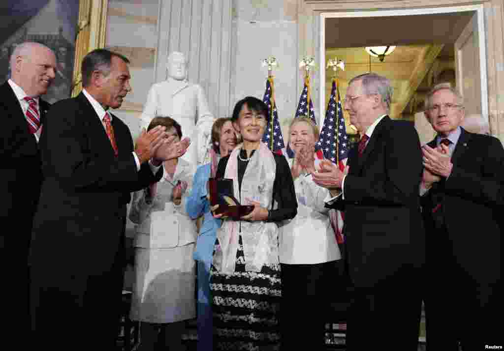 Burma's democracy leader Aung San Suu Kyi holds her Congressional Gold Medal after it was presented to her by House Speaker John Boehner (R-OH) (2nd L), at the U.S. Capitol in Washington, September 19, 2012.