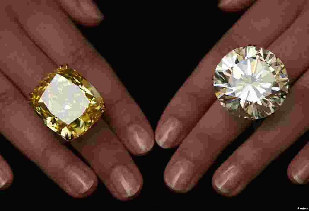 A model poses with a vivid yellow 100.09 carat diamond (L) and a 103.46 carat diamond ring during an auction preview at Sotheby's in Geneva, Switzerland. These items are expected to reach between $15,000,000 to 25,000,000 and $3,500,00 to 5,000,000 when they go on sale in Geneva on May 13.