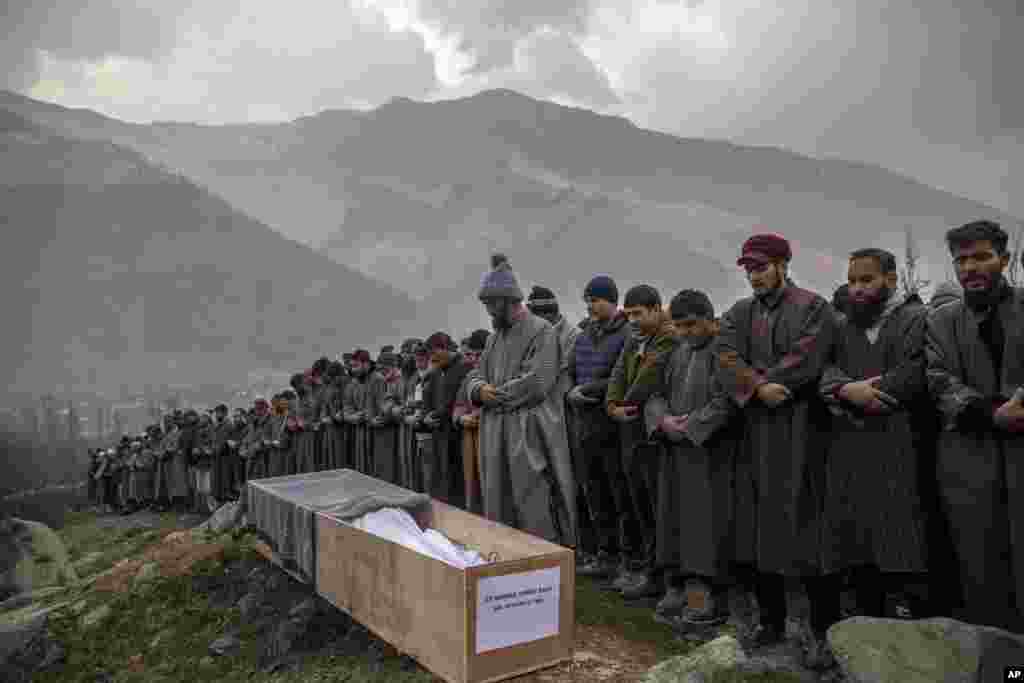 Relatives and neighbors pray by the body of Rameez Ahmad, a policeman who was killed in Monday's gun attack, during his funeral in Yachama, northeast of Srinagar, Indian-controlled Kashmir.