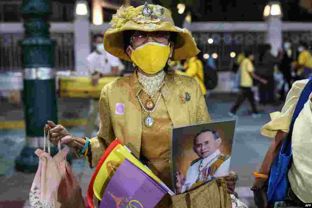 A royalist supporter holds a portrait of the late king Bhumibol Adulyadej while waiting for the motorcade of Thailand's King Maha Vajiralongkorn to pass in Bangkok.