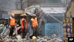 Rescuers walk in the rubble at the scene of a five-story collapsed building in the Huruma neighborhood of Nairobi, June 3, 2018. 
