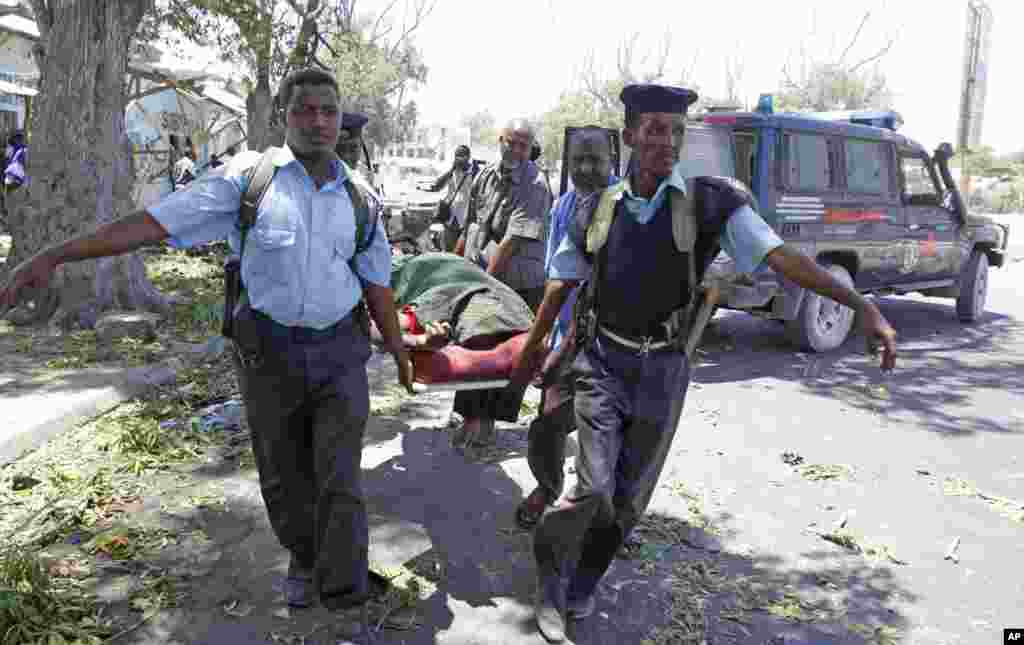 Police officers carry a body after a suicide bomber blew himself up near a cafe in Mogadishu, Feb. 27, 2014.