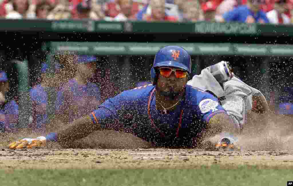 Pemain bisbol dari klub New York Mets, Jordany Valdespin, meluncurkan tubuhnya menyentuh home plate untuk membuat skor dalam RBI ganda oleh Daniel Murphy selama inning ketiga permainan bisbol melawan St Louis Cardinals di St Louis, 16 Mei 2013.