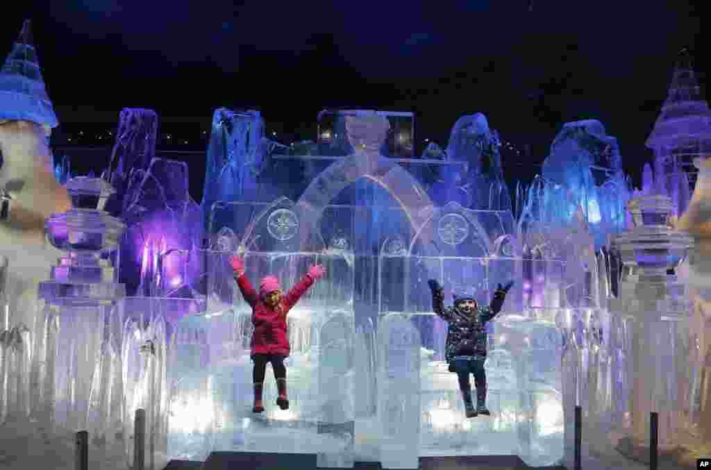 Scarlett (4 tahun) dan Zoe (3) menikmati duduk di atas patung es pada pembukaan taman Wonderland's Magical Ice Kingdom di Hyde Park, London.