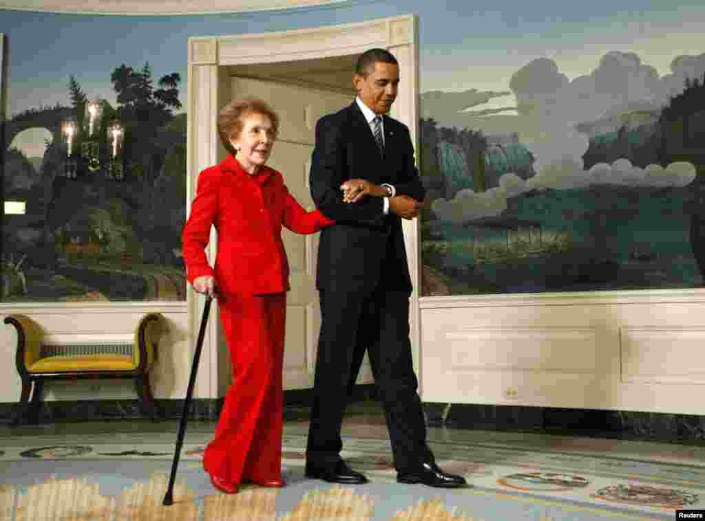 Presiden AS Barack Obama menggandeng mantan ibu negara Nancy Reagan ke upacara penandatanganan undang-undang Komisi Satu Abad Ronald Reagan untuk perayaan ulang tahun ke-100 mantan presiden itu, di Gedung Putih di Washington, 2 June 2009. (Reuters/Kevin Lamarque)