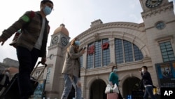 2020年4月7日武汉恢复交通前夕，带着行李的旅客走过汉口火车站。