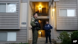 Un alguacil del condado Douglas y un policía estatal de Oregon hacen guardia delante del apartamento del hombre que atacó el colegio universitario Umpqua en Roseburg, Oregon. Viernes 2 de octubre de 2015.