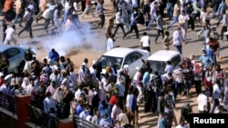 Demonstrators run from teargas lobbed to disperse them as they march along the street during anti-government protests in Khartoum, Sudan, Dec. 25, 2018. 
