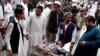People stand near a man injured from an explosion, at a local hospital in Pakistani tribal area of Parachinar, May 6, 2013.