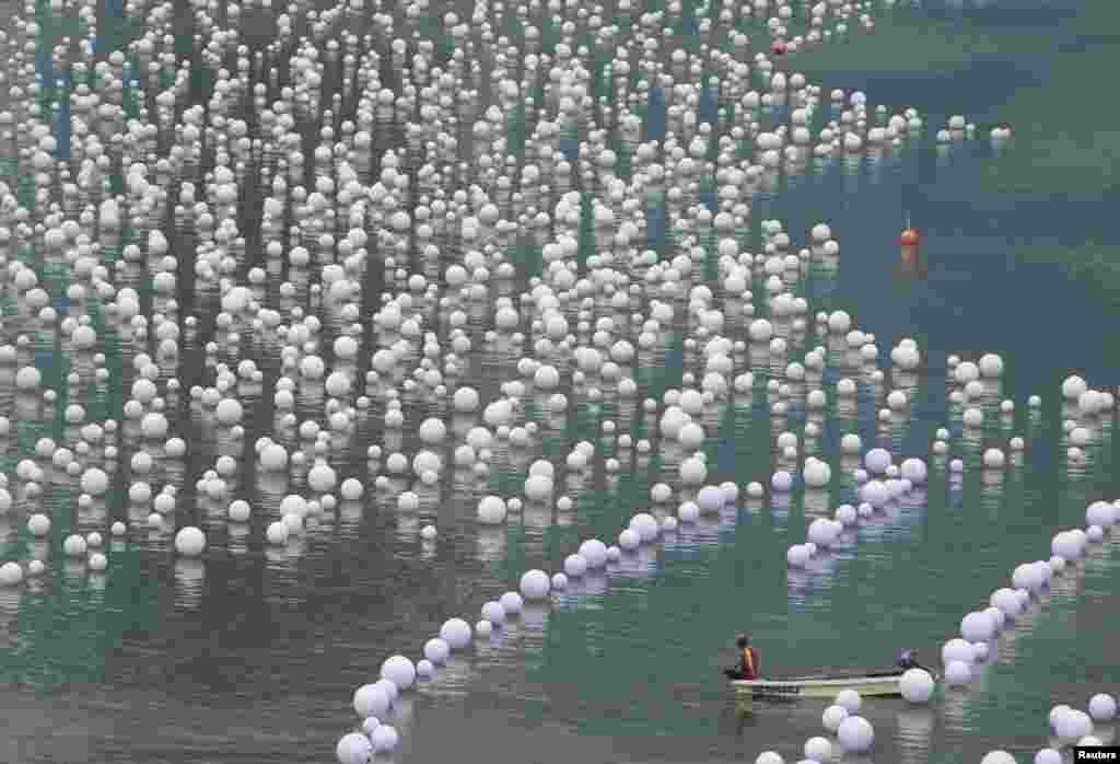 Seorang pekerja tampak beristirahat di perairan Teluk Marina di Singapura yang penuh dengan bola-bola permohonan tahun baru 2014 dari warga setempat. 