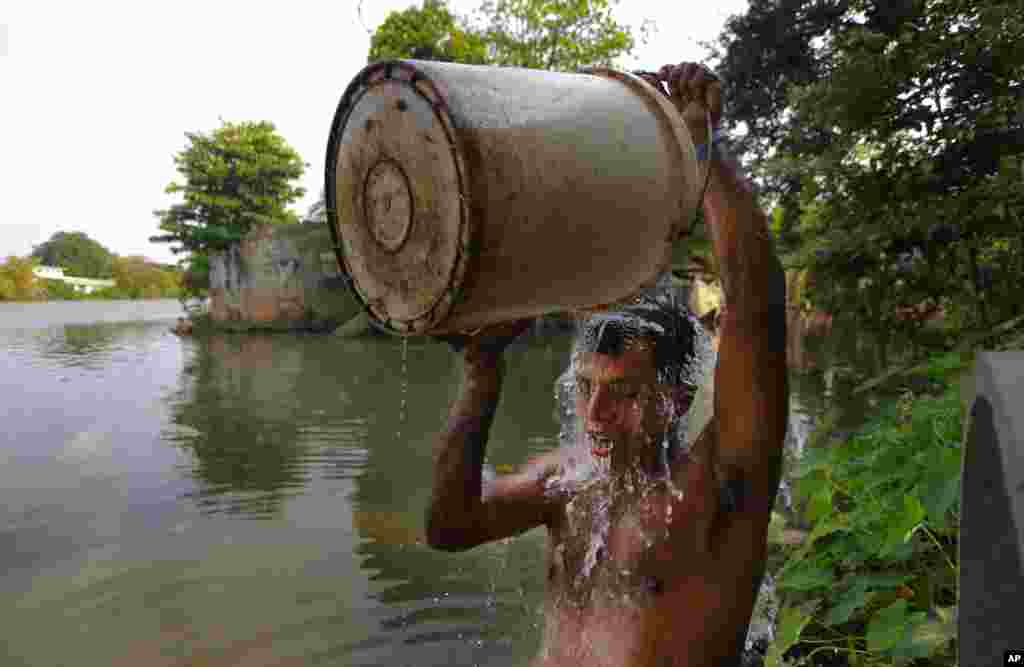 Seorang pria Sri Lanka mandi dengan air dari pipa air minum yang bocor di dekat sungai yang penuh polutan di Kolombo.