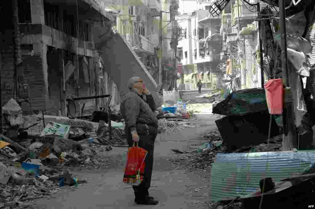 Seorang penduduk Suriah di Homs menatap bangunan yang rusak setelah kembali ke daerah Christian Hamidiyehdi, kota tua yang terletak di kota pusat Suriah, setelah kelompok pemberontak terakhir meninggalkan kota tua Homs di bawah kesepakatan evakuasi yang memberikan kemenangan simbolis bagi pemerintah . 