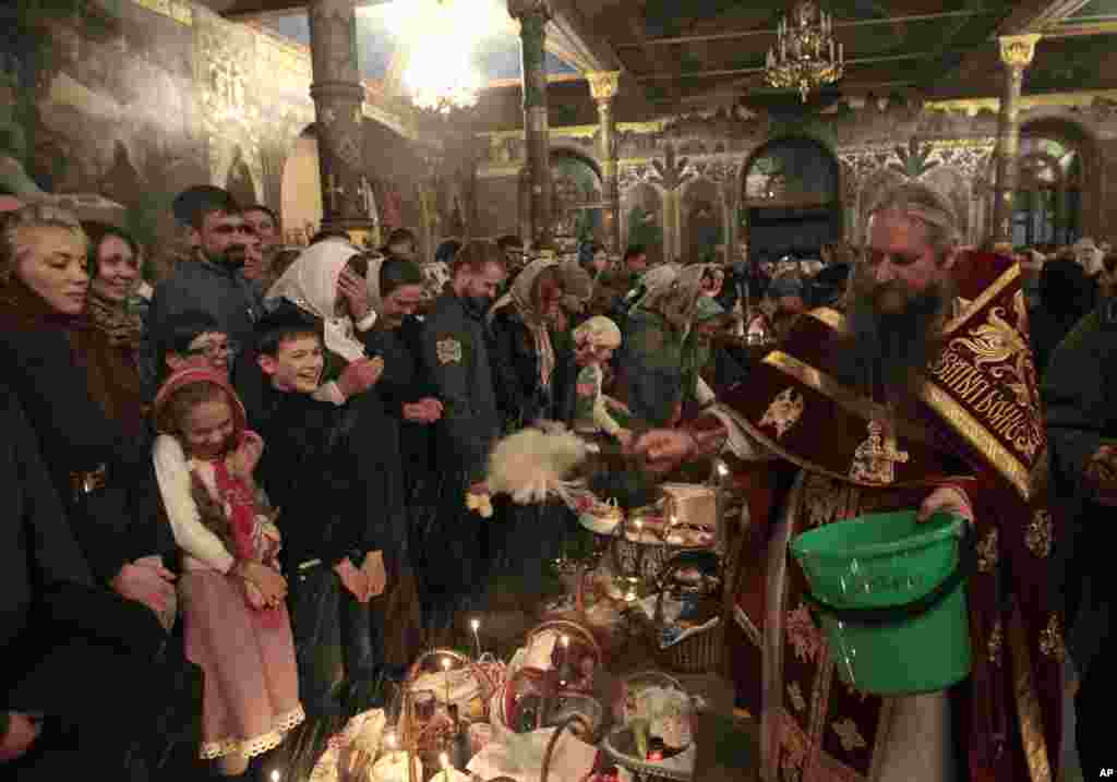 An Orthodox priest blesses traditional Easter cakes and painted eggs prepared for Easter celebrations in the Kyiv-Pechersk Lavra church (Cave Monastery), Kyiv, Ukraine, April 20, 2014. 