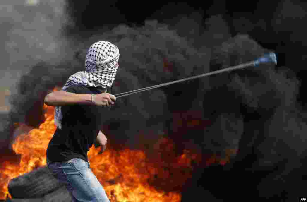Seorang demonstran Palestinian melempar batu dengan ketapel ke arah pasukan Israel dalam aksi protes menentang perampasan tanah Palestina oleh Israel di Kfar Qaddum, dekat Nablus, Tepi Barat.