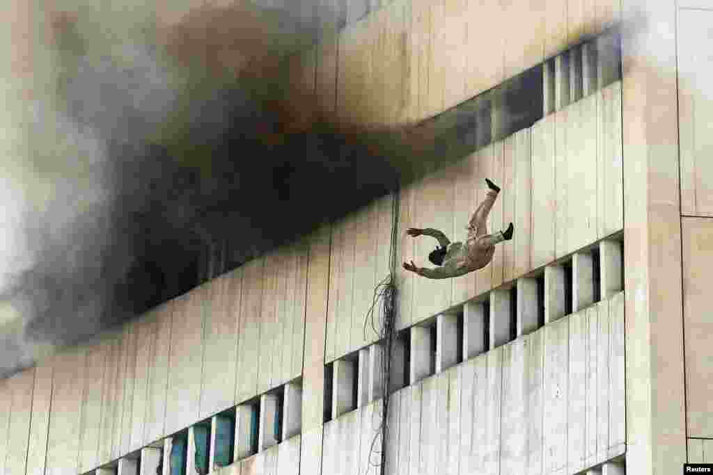 Seorang pria terjatuh dari lantai atas gedung yang terbakar di Lahore, Pakistan. Api berkobar dari lantai 7 gedung LDA plaza di Lahore dan dengan cepat menyebar ke seluruh gedung, membuat banyak orang terperangkap di dalam gedung.