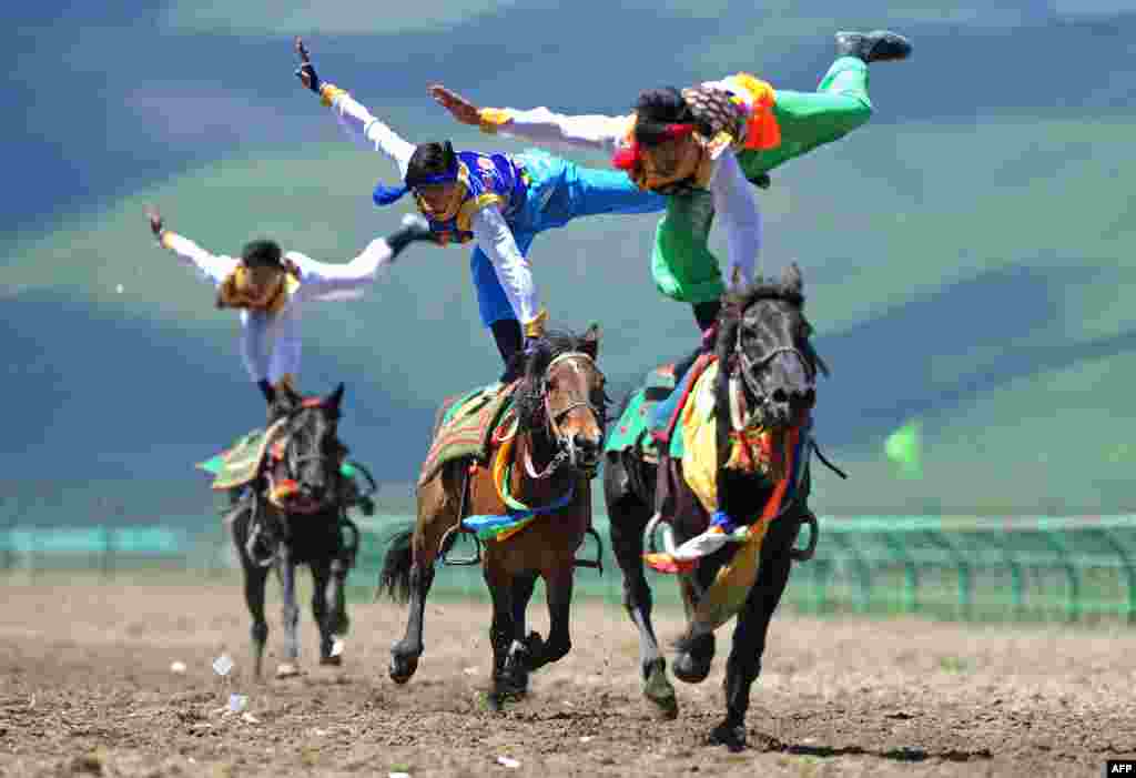 Tiga pria beraksi dalam festival menunggang kuda tradisional di Ngawa, Sichuan, China.
