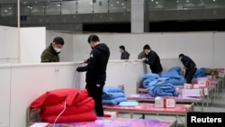Workers set up infrastructure at the Wuhan International Conference and Exhibition Center to convert it into a makeshift hospital to receive patients infected with the new coronavirus, in Wuhan, Hubei province, China February 4, 2020. Picture taken…